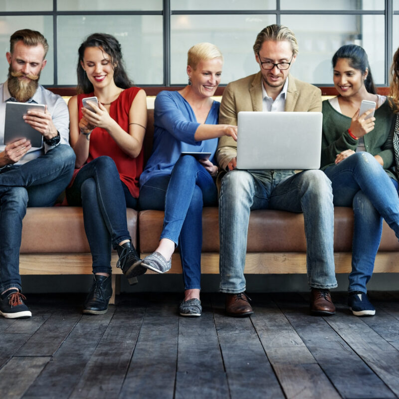 group of people on couch using their devices to read about interoperability