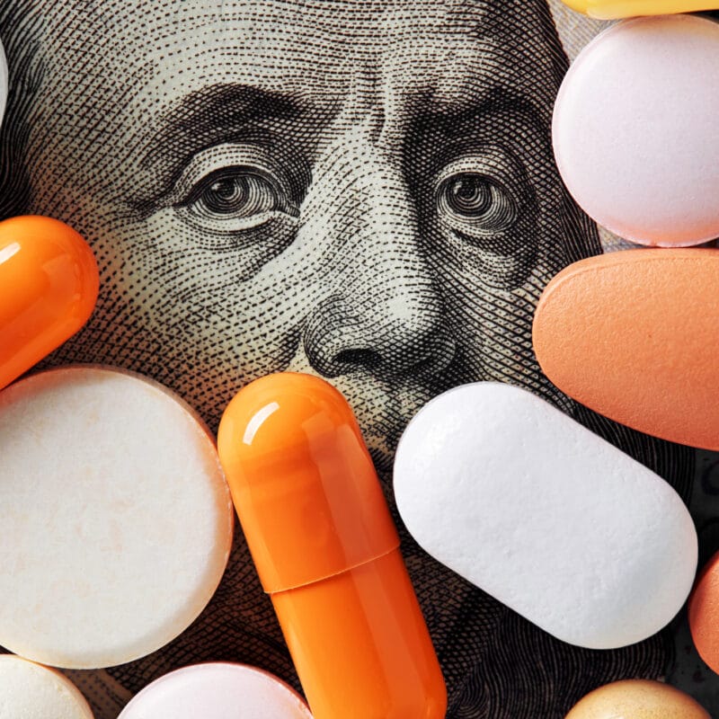 healthcare cost concept. Colorful medical pills cover Benjamin Franklin's face on one hundred american dollar bill.