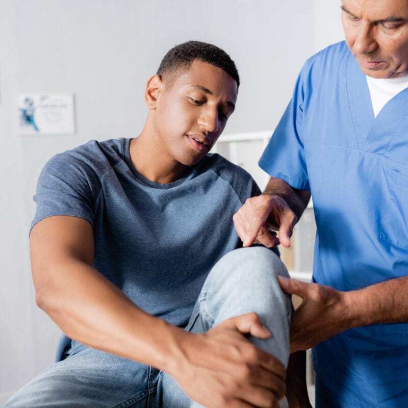 male patient with doctor examining knee